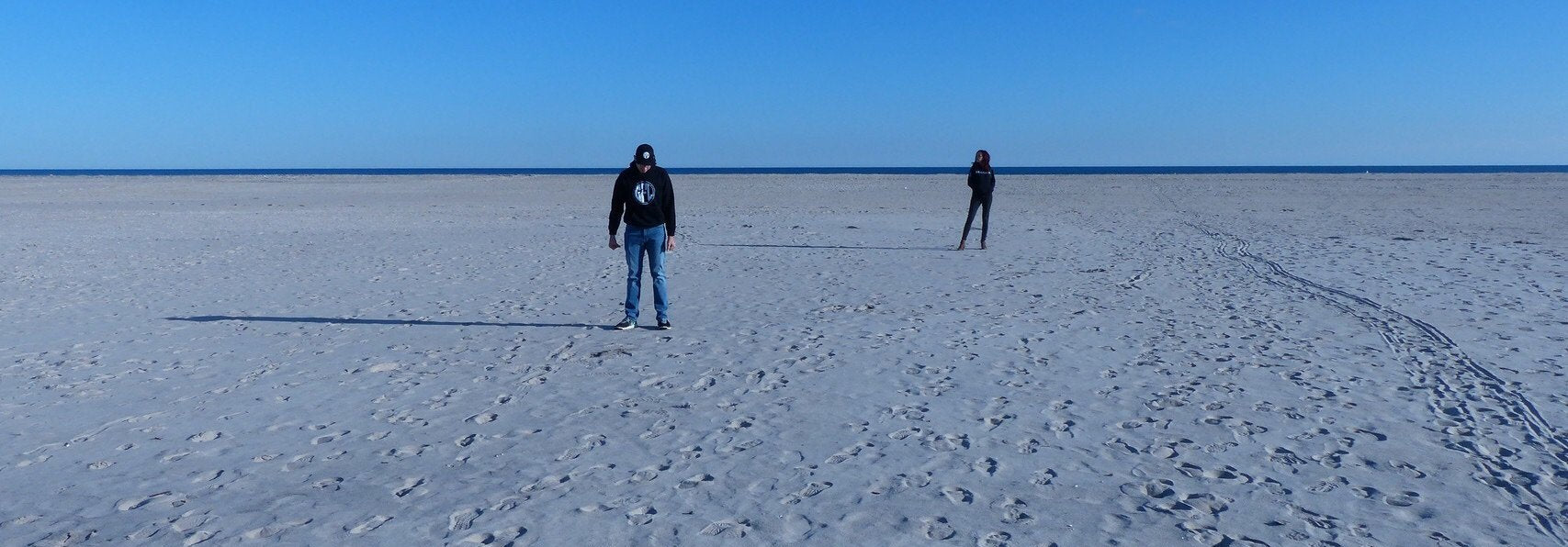 Man in the front of the image, woman in the background, wearing GFL sweaters on the beach