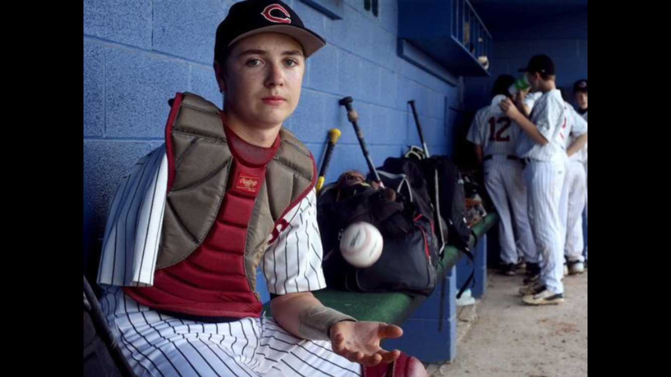 Luke Terry sitting in baseball dugout with a baseball in hand