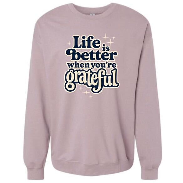 Pink sweatshirt with 'Life is better when you're grateful' text on a white background