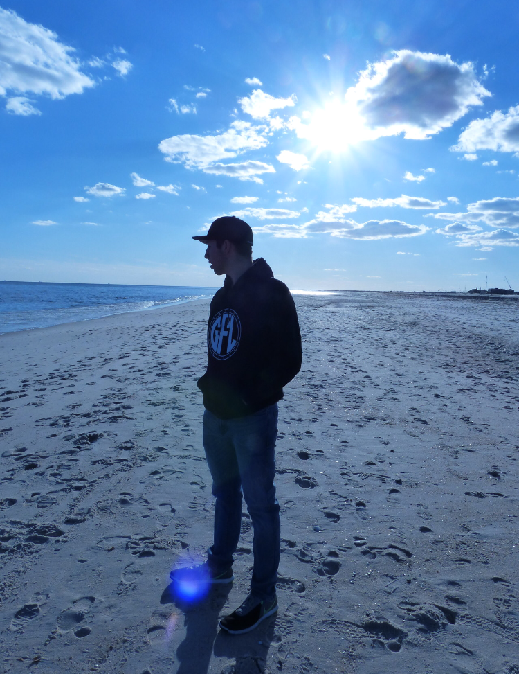 Man, on the beach, wearing a GFL sweater