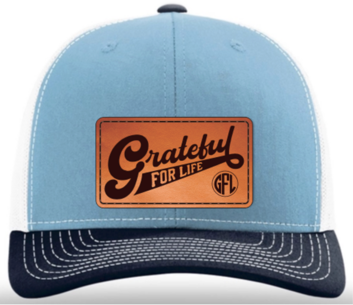Blue cap with a brown leather patch featuring 'Grateful for Life' text on a white background